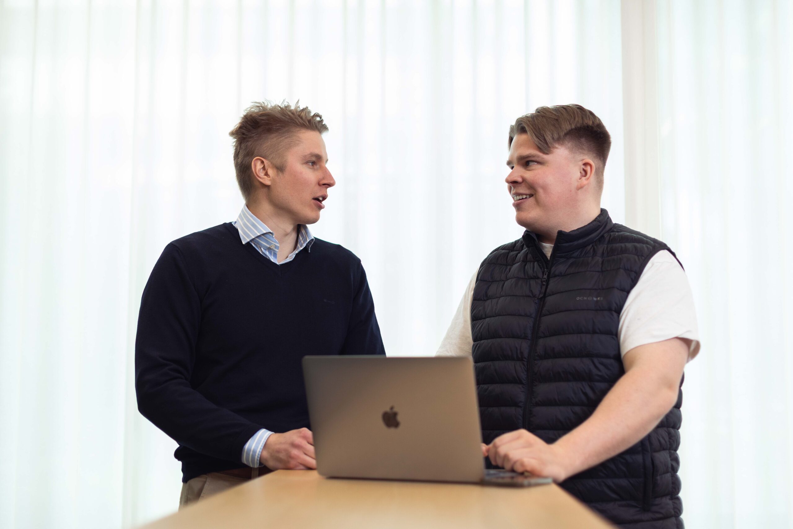 Kaksi Audiensin työntekijää keskustelee kannettavan tietokoneen ääressä